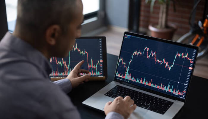 Risks Involved in Cryptocurrency for Investment 1 - Incryptocoin Investor analyzing live price charts on laptop and tablet while researching cryptocurrency for investment.