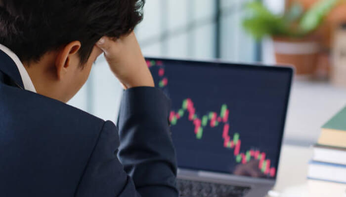 Impact of Bitcoin Crash on Investors 1 - Incryptocoin Investor stressed and worried about the Bitcoin crash, looking at a downward crypto market graph on a laptop screen.